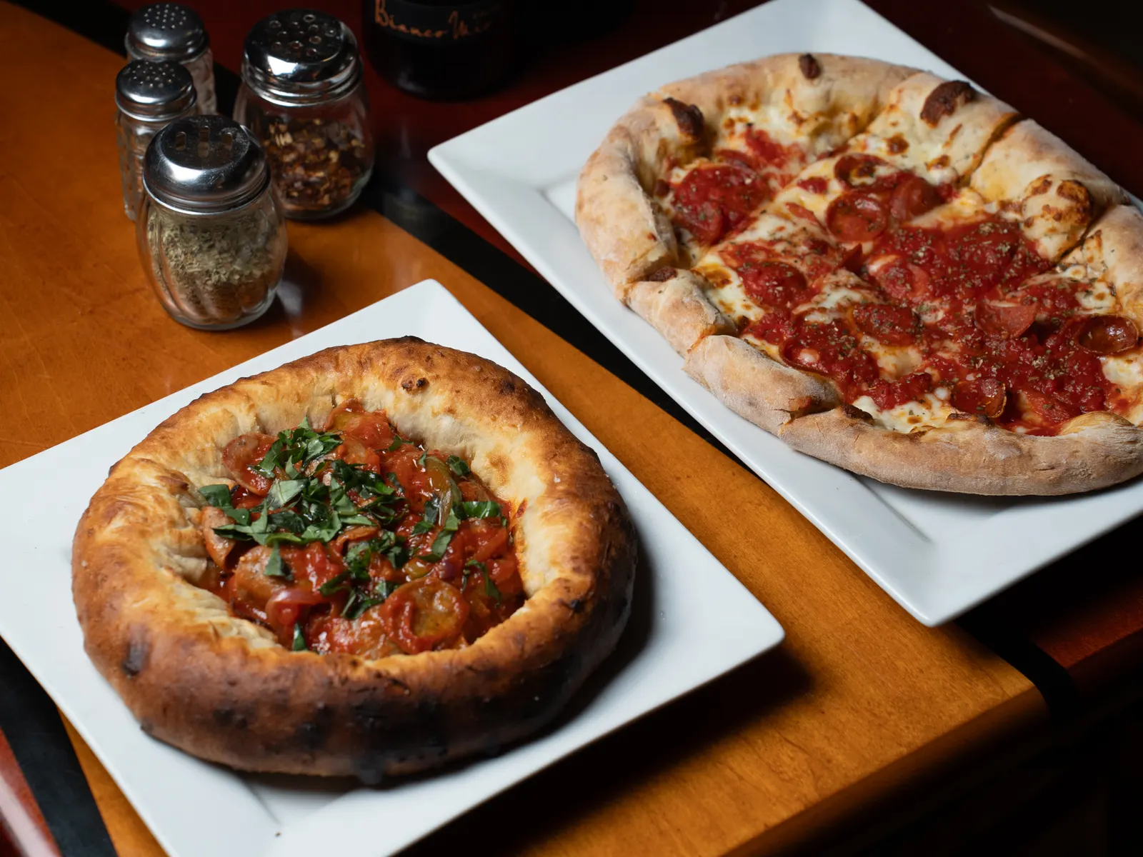 Pizza bowl and a pizza on the cherry-red table with the tricolor stripe at Pulcinella, Kendall
