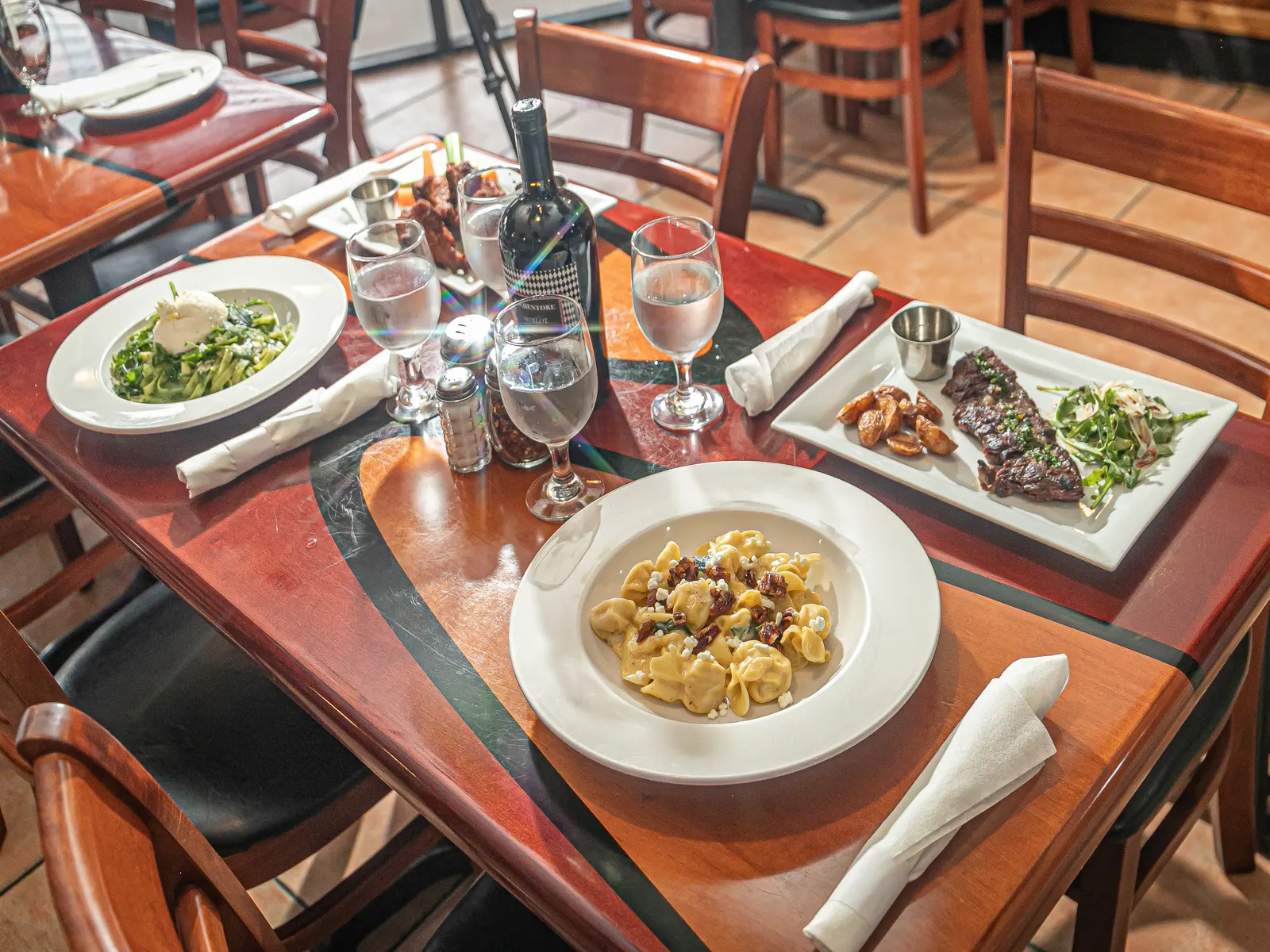 The dining room at Pulcinella: cherry-red tables with the tricolor stripe, terracotta floor and the storefront window